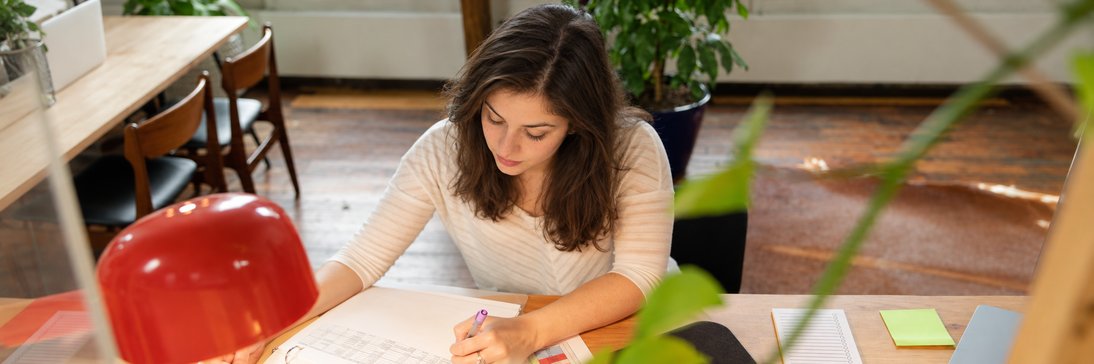 Jess sitting at a desk with papers and a red lamp