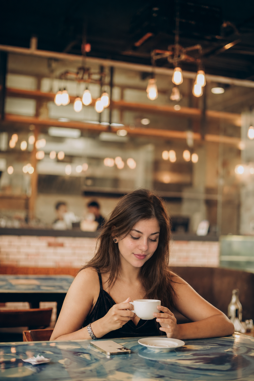 Jess holding a coffee cup at a café table